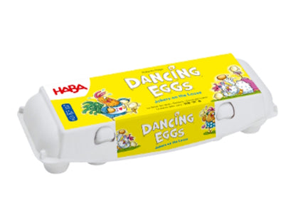 Op een wit plastic eierdoosje met de naam "Eierdans" van Haba Spellen staan speelse kippen en eieren op een felgele achtergrond, met de merknaam in rood linksboven - een leuke keuze voor dit levendige behendigheidsspel.
