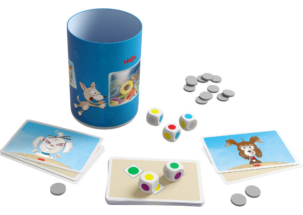 Een Dobbelbeker - Woef Woef container van Haba Spellen heeft een blauw cilindervormig ontwerp met dierenillustraties, omringd door kleurrijke dobbelstenen, grijze lopers en speelkaarten met cartoondieren op een witte achtergrond.